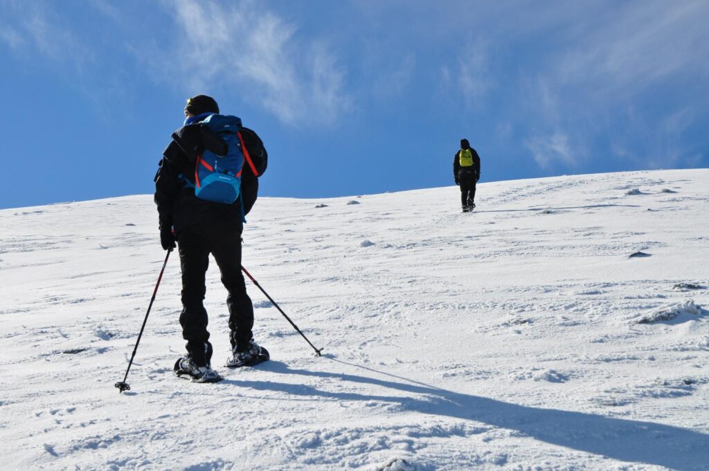Escursionista con ciaspole e bastoncini su un pianoro innevato