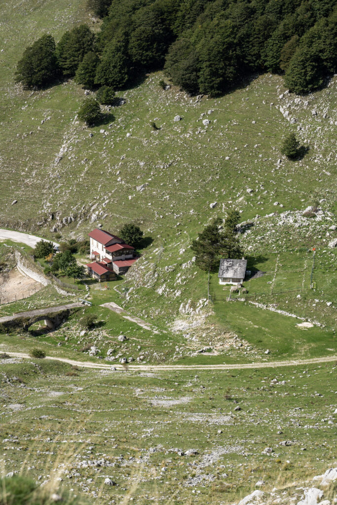 Pendio erboso con una baita e un rifugio in lontananza