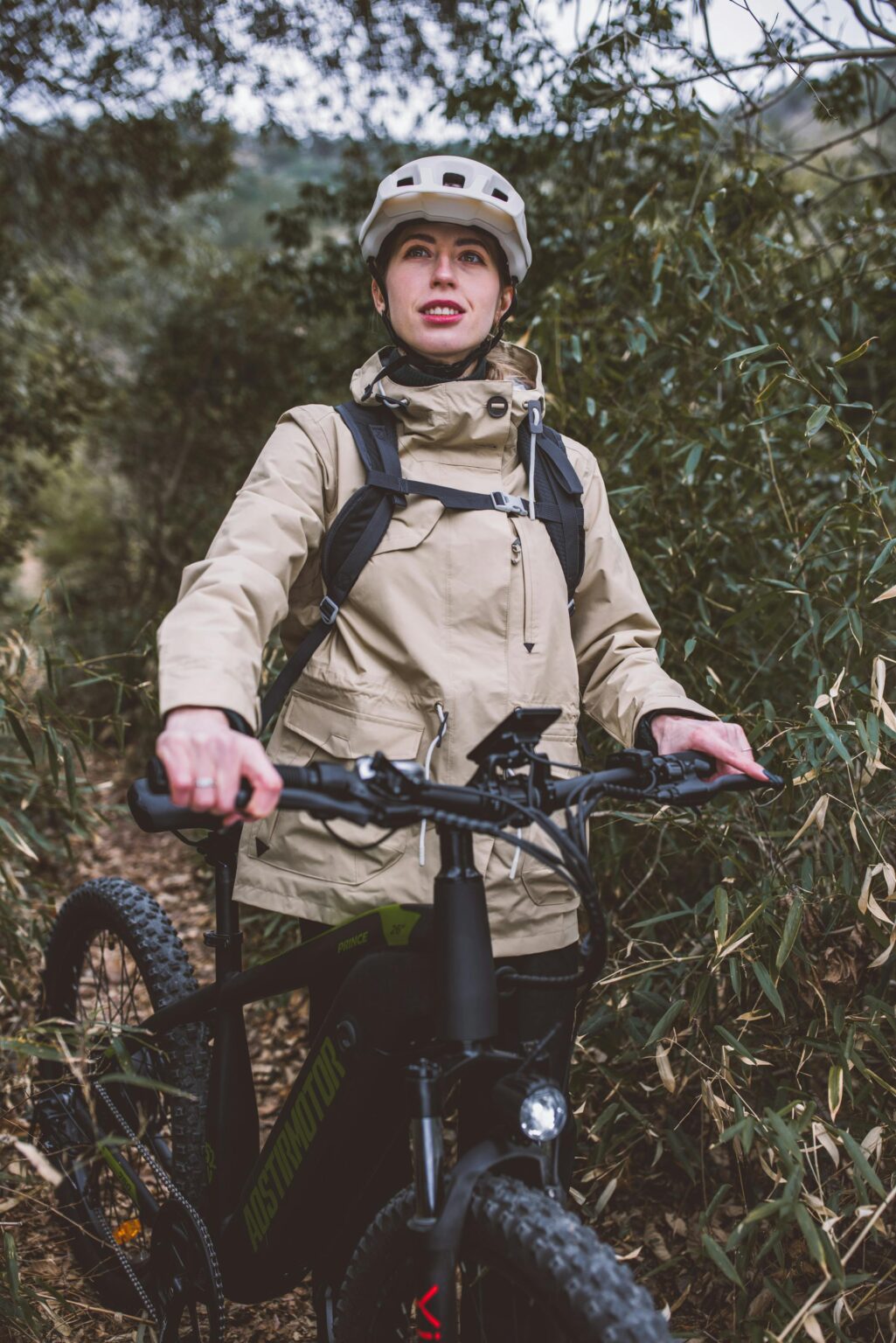 Ciclista con casco e giacca beige in e-bike nel bosco