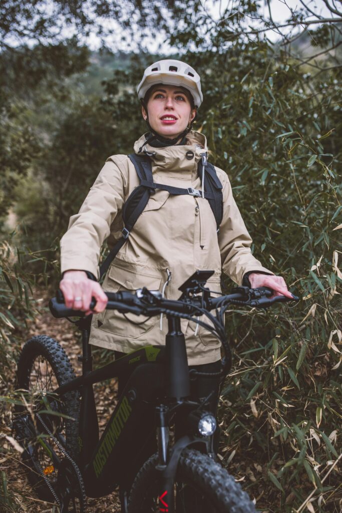 Ciclista con casco e giacca beige in e-bike nel bosco