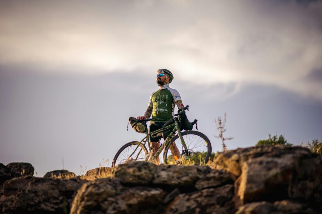 Cyclist with road bike on a rock top, under a cloudy sky